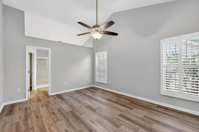 a view of an empty room with window and wooden floor