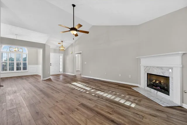 a view of empty room with wooden floor fireplace and window