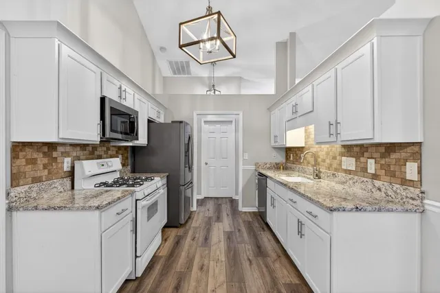 a kitchen with stainless steel appliances granite countertop a stove oven and a white cabinets