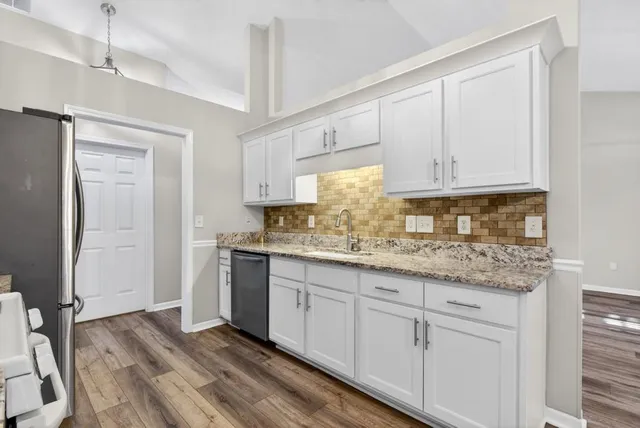 a kitchen with granite countertop white cabinets and a sink