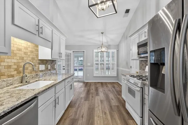 a large kitchen with stainless steel appliances granite countertop a lot of counter space and wooden floors