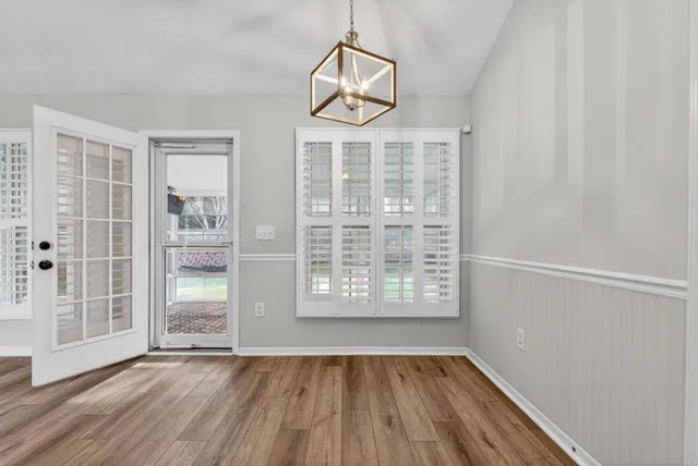 an empty room with wooden floor cabinet and windows