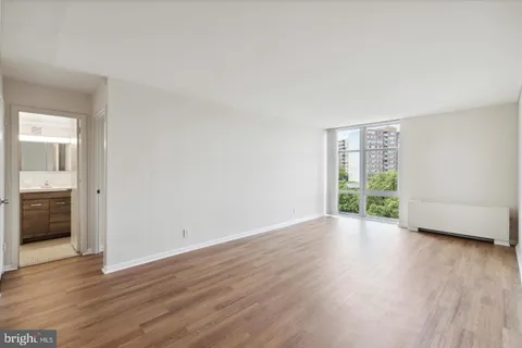 a view of an empty room with a window and wooden floor