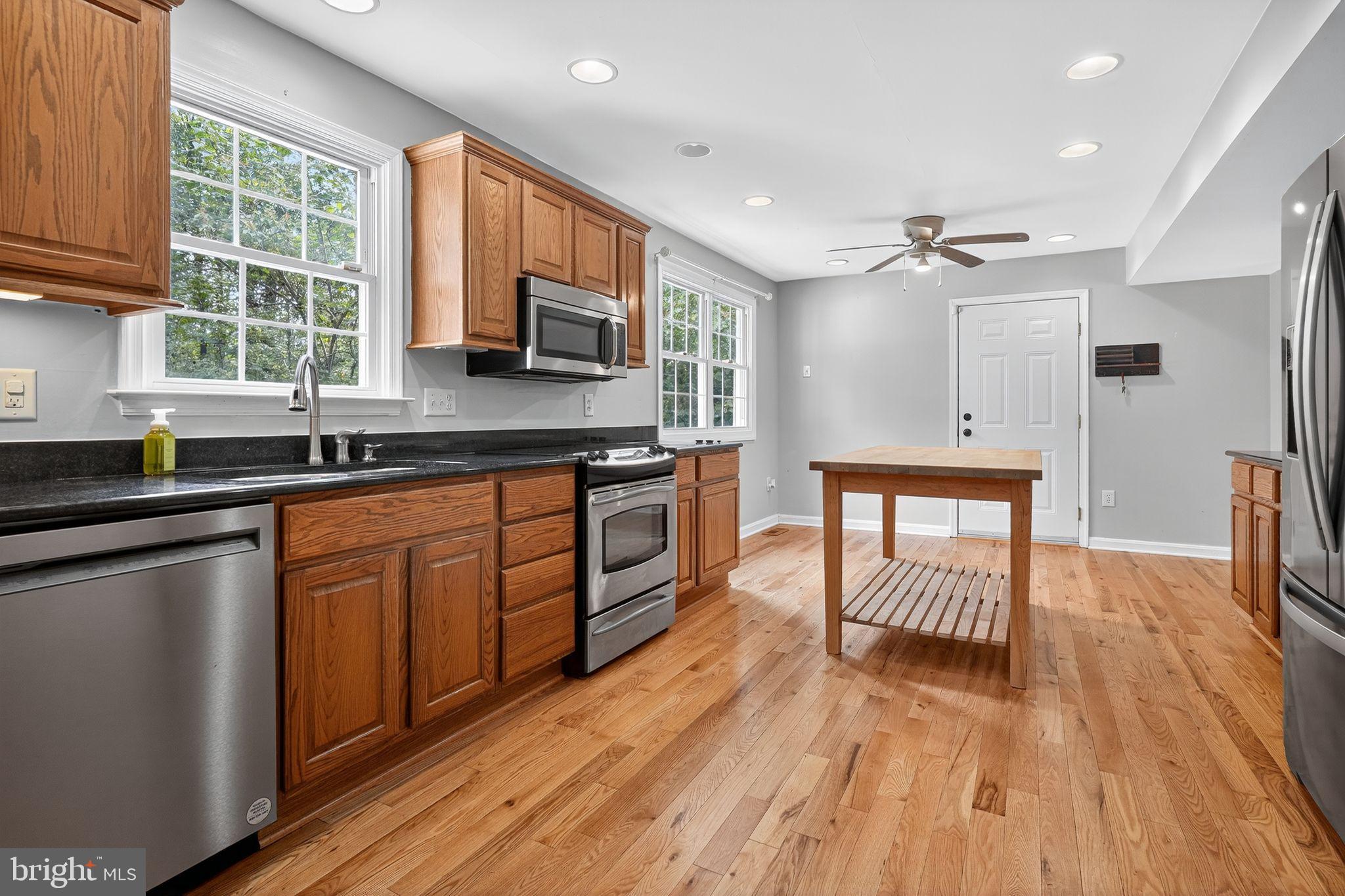 2196 Hallmark Court Gambrills, MD 21054 - Photo 3 of 14 a kitchen with stainless steel appliances granite countertop hardwood floor sink stove dining table and chairs
