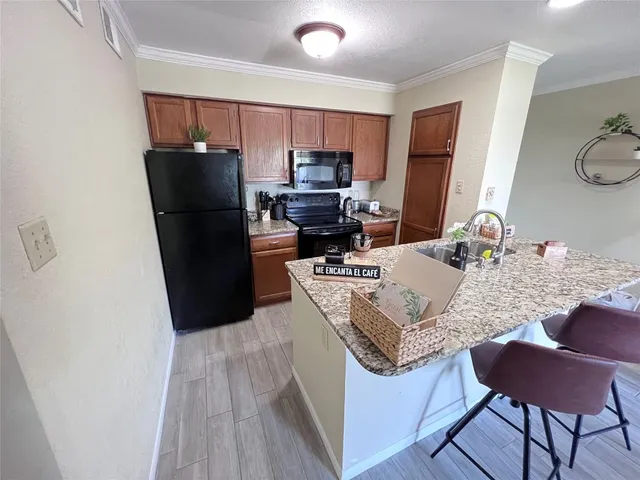 a kitchen with stainless steel appliances granite countertop a refrigerator a stove a sink and a dining table with wooden floor