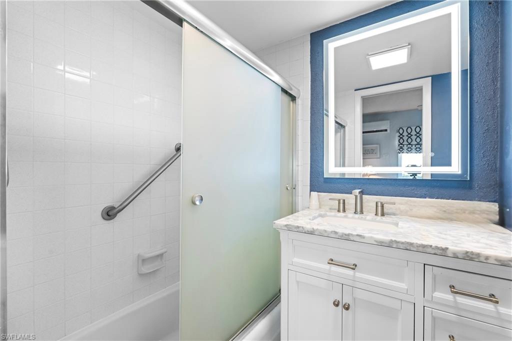 87 North Collier Boulevard, Unit B4 Marco Island, FL 34145 - Photo 14 of 31 a bathroom with a granite countertop sink a mirror and a bathtub