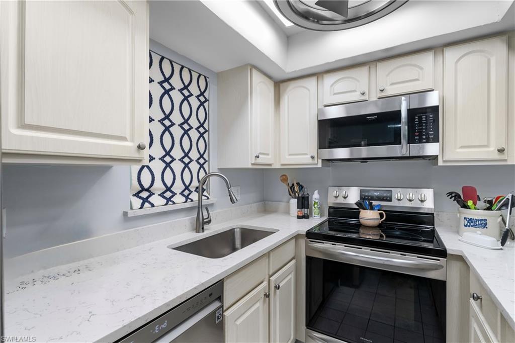 87 North Collier Boulevard, Unit B4 Marco Island, FL 34145 - Photo 3 of 31 a kitchen with stainless steel appliances granite countertop a sink a stove a microwave and cabinets