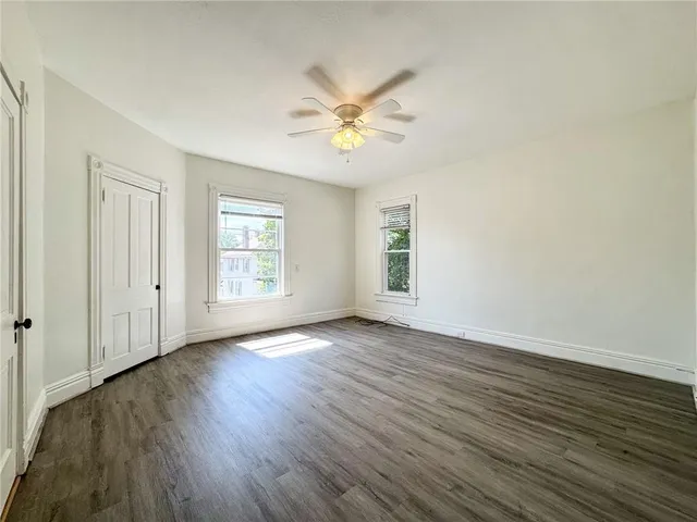 a view of an empty room with window and wooden floor