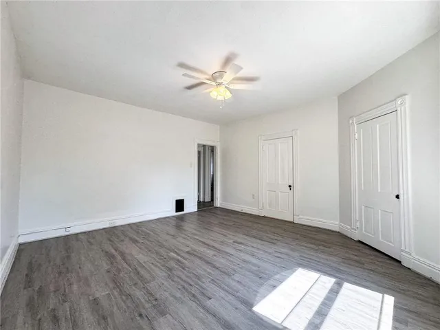 a view of a room with wooden floor and a ceiling fan