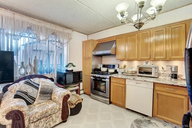 a kitchen with furniture a chandelier and stainless steel appliances