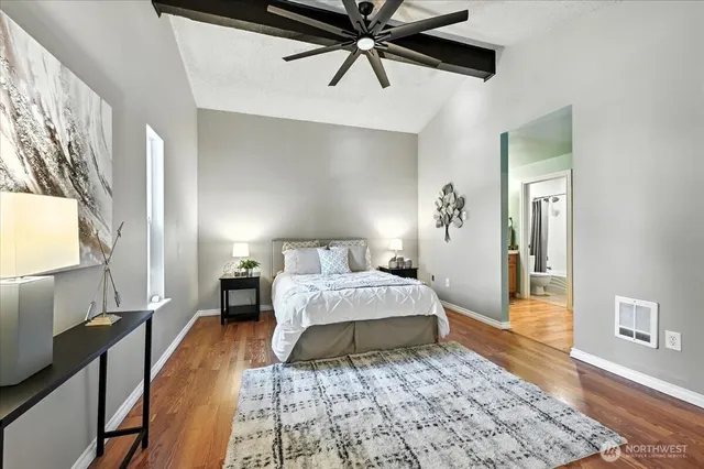 a spacious bedroom with a bed and a lamp on table