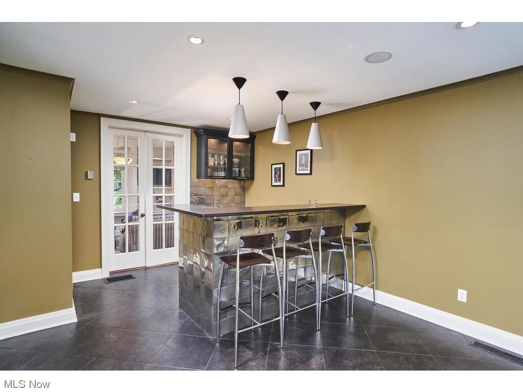 Piano Bar with pendant lighting, dark tile flooring, and french doors