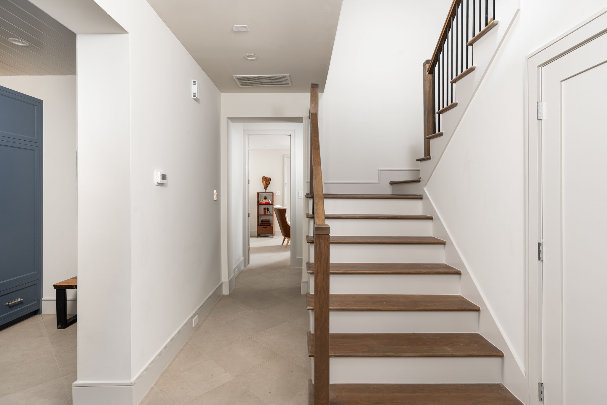 1215 West Pierce Street Houston, TX 77019 - Photo 11 of 40 The hallway to the first floor bedroom shows off the large-format tile, deep baseboards, and stained oak stair treads.