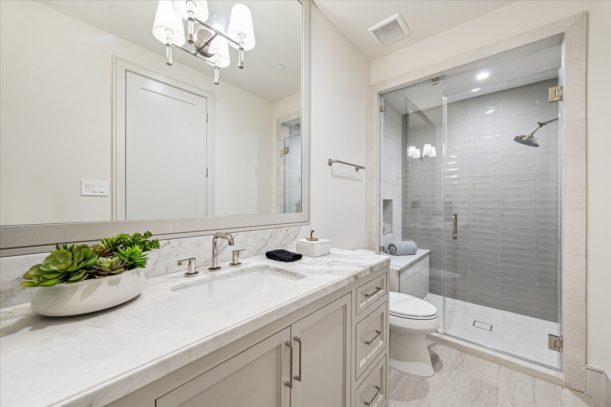 1215 West Pierce Street Houston, TX 77019 - Photo 14 of 40 The first floor bathroom features Ecosystems Jute Vein porcelain tile with Aquarelle Griege horizontal tile accent wall, large format shower head, and frameless glass enclosure.