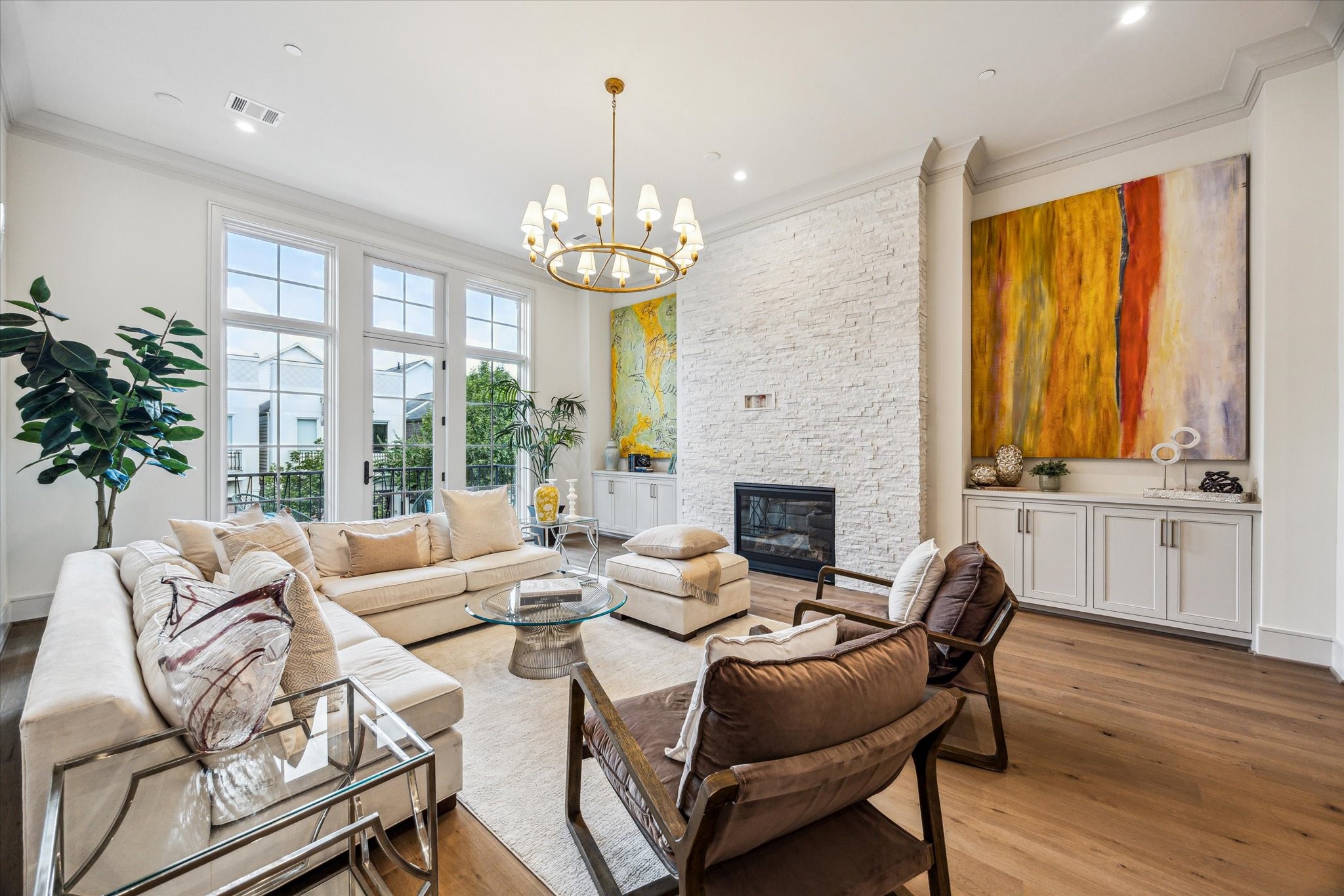 1215 West Pierce Street Houston, TX 77019 - Photo 2 of 40 The lavish living room, complete with custom built-ins, stacked stone fireplace, and floor-to-ceiling windows. Twelve-foot ceilings, elegant crown moulding, and understated chandelier by Ziba create warmth and elegance.