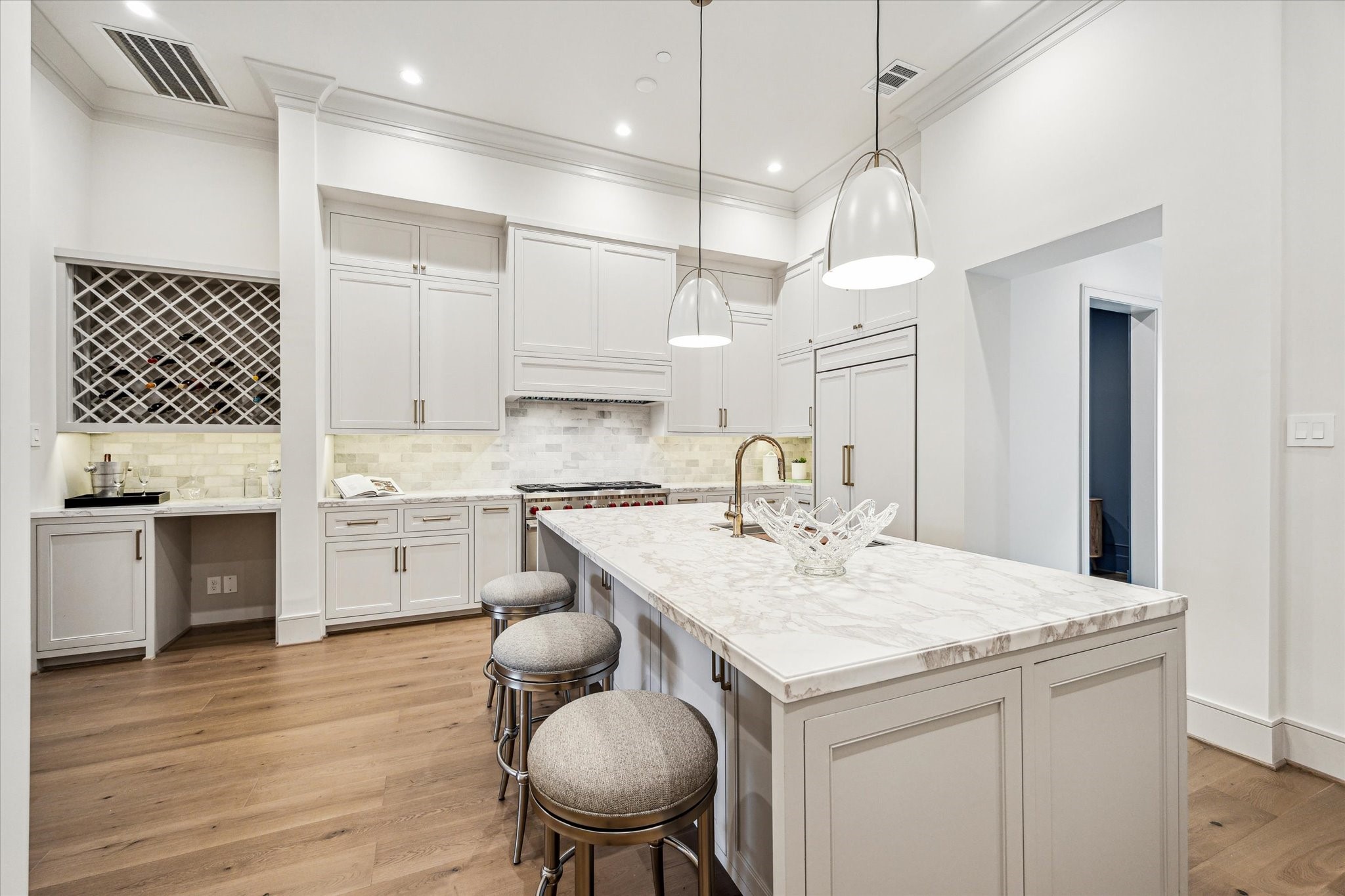 1215 West Pierce Street Houston, TX 77019 - Photo 21 of 40 One side of the kitchen island features both storage and a counter for casual dining. Norman pendants light the island. At the back right is the walk-in pantry, and at the left is the custom-paneled Sub-Zero refrigerator freezer. The Wolf range features 2 ovens, six burners, and an infrared griddle.