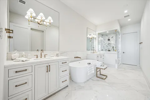a spacious bathroom with a double vanity sink mirror and bathtub