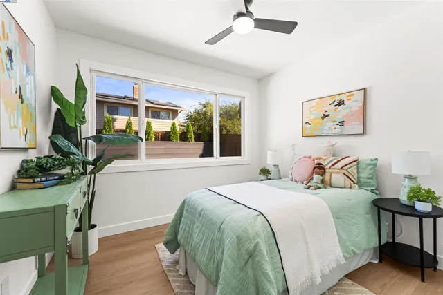a bedroom with a bed table flowerpot and window