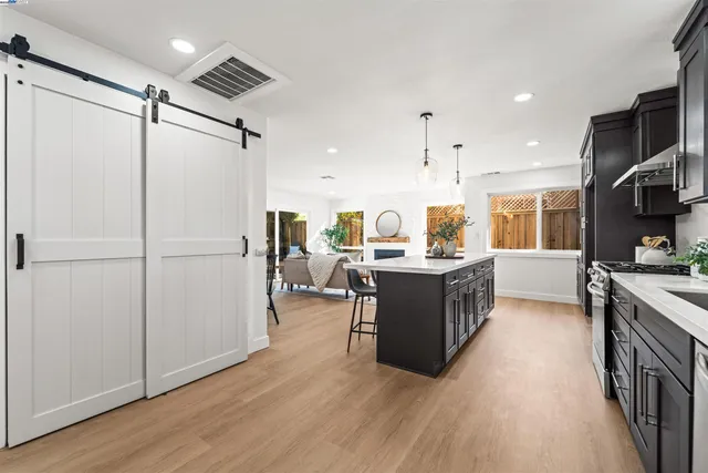 a kitchen with kitchen island wooden floors appliances and cabinets