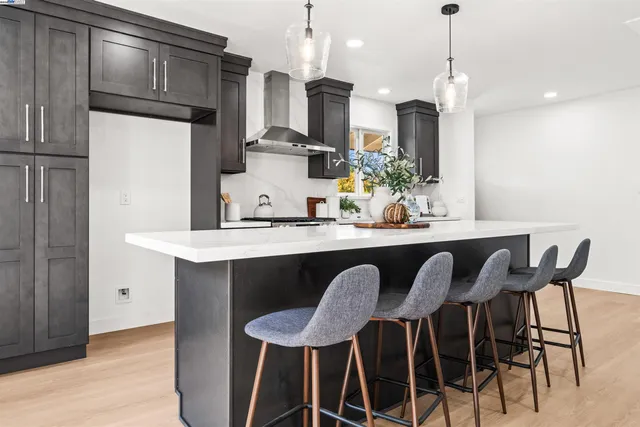 a kitchen with stainless steel appliances kitchen island granite countertop a dining table chairs and white cabinets