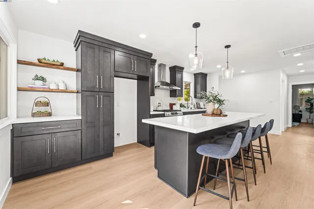 a kitchen with stainless steel appliances kitchen island granite countertop a refrigerator a sink dishwasher a dining table and chairs with wooden floor