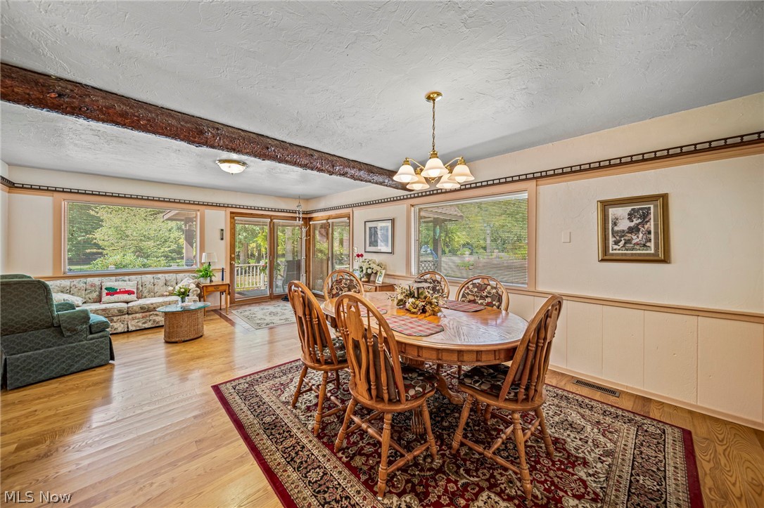8801 Bunker Road Orwell, OH 44076 - Photo 23 of 50 Dining room featuring a textured ceiling, a wainscoted wall, light wood finished floors, a chandelier, and beamed ceiling