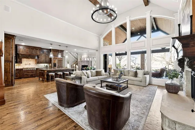 a living room with furniture a rug kitchen view and a large window