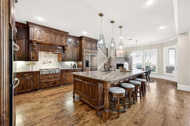 a kitchen with stainless steel appliances granite countertop a stove top oven a sink a dining table and chairs with wooden floor