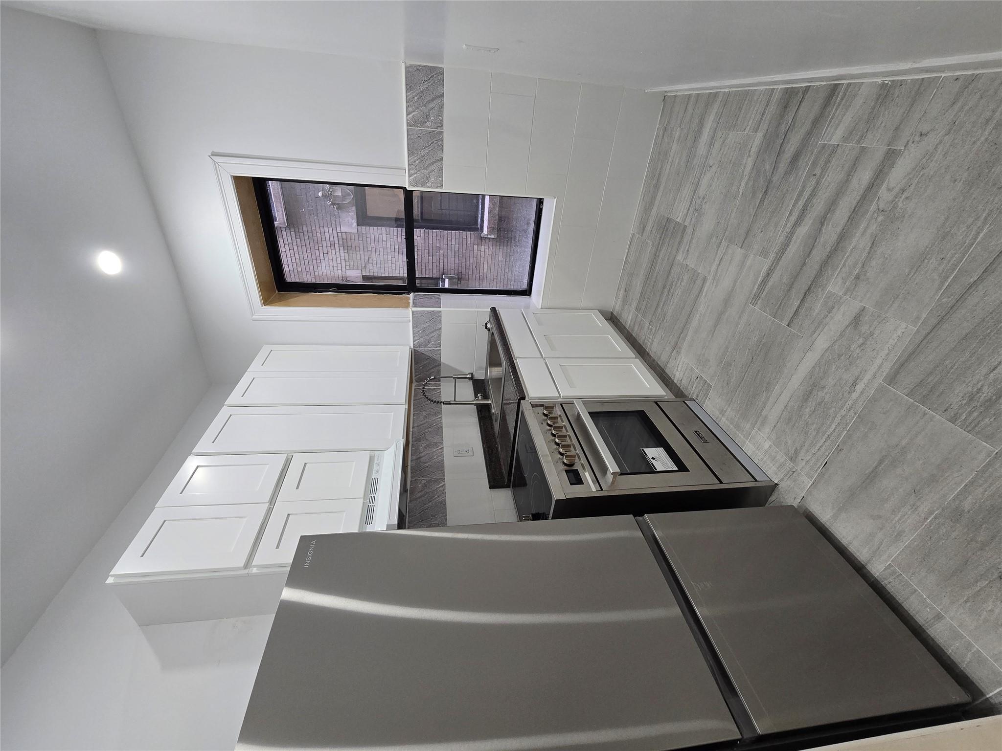 618 Riverside Drive, Unit 24 Manhattan, NY 10031 - Photo 8 of 16 Kitchen featuring wall chimney range hood, white cabinetry, fridge, stove, and a sink