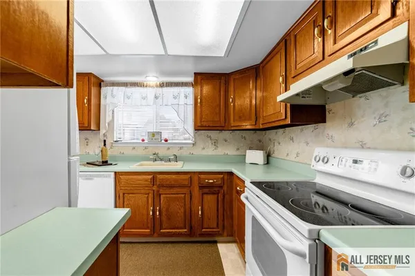 a kitchen with a sink a stove cabinets and a window