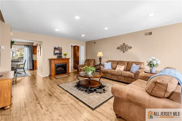 a living room with furniture a fireplace and a dining table with wooden floor