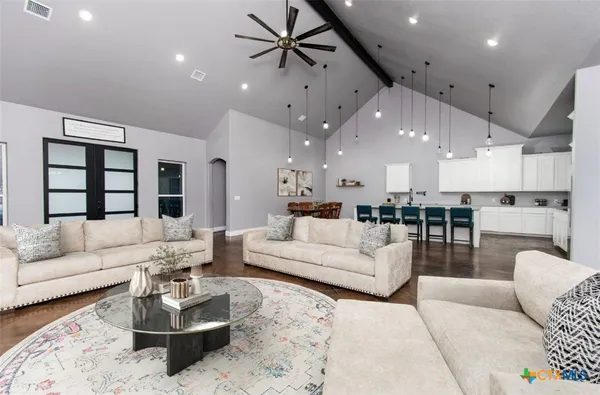 a living room with furniture kitchen view and a chandelier