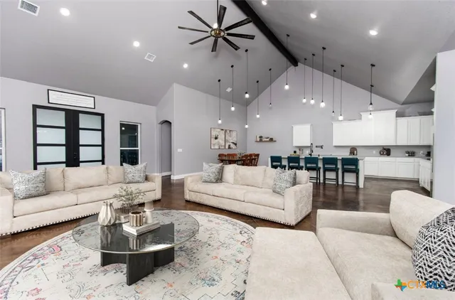 a living room with furniture kitchen view and a chandelier