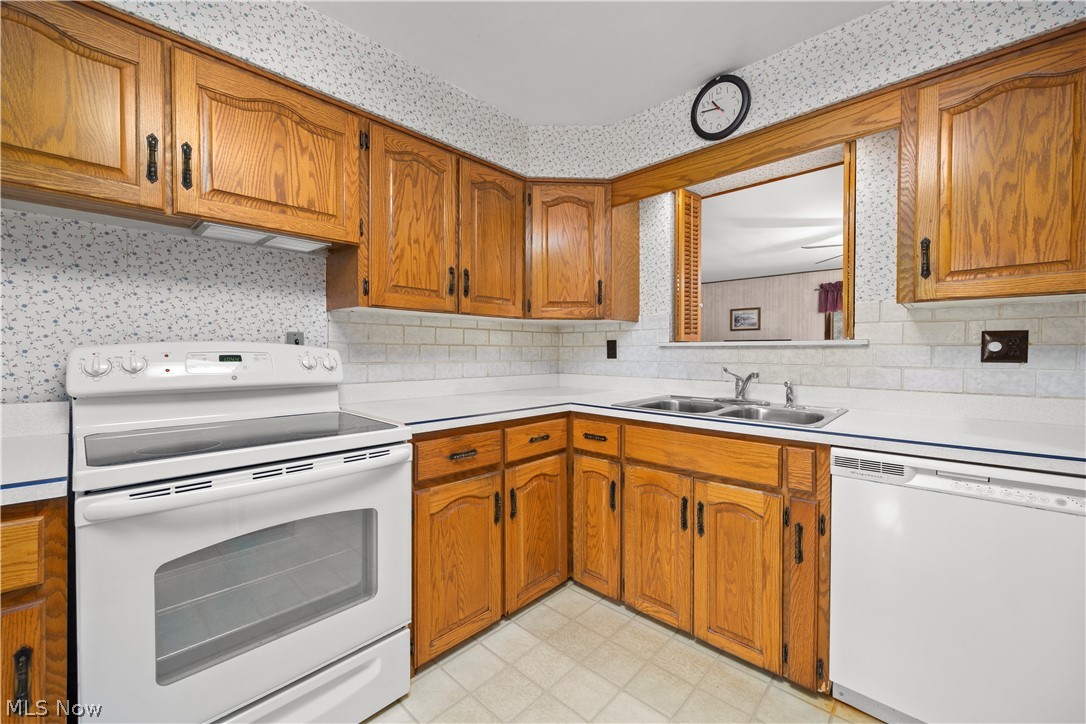 36141 Aurensen Road North Ridgeville, OH 44039 - Photo 6 of 24 Kitchen featuring sink, tasteful backsplash, white appliances, and light floors. Open above sink looks into family room