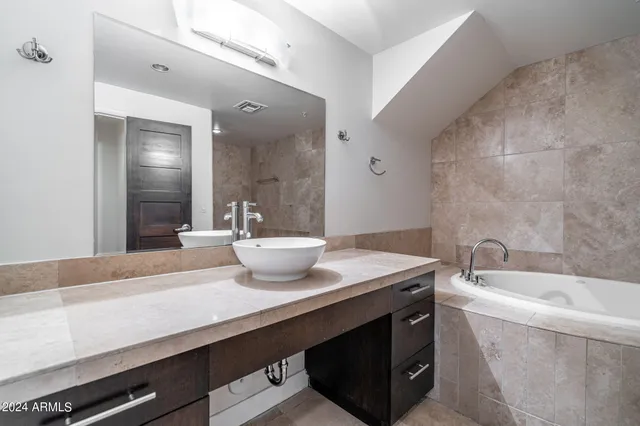 a bathroom with a granite countertop sink a large mirror and bathtub
