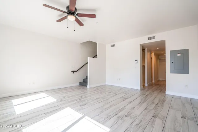 a view of empty room with wooden floor and fan