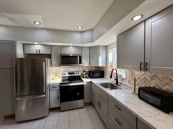 a kitchen with stainless steel appliances granite countertop a refrigerator a sink dishwasher a stove top oven a refrigerator with wooden floor