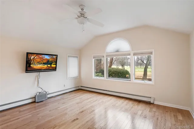 an empty room with wooden floor chandelier and windows