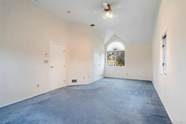 an empty room with windows and ceiling fan