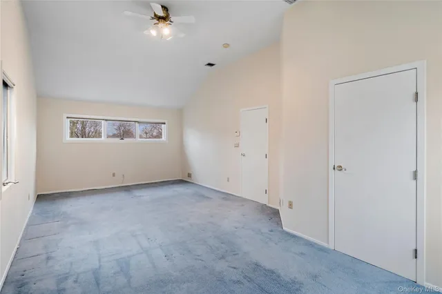 an empty room with a ceiling fan and window