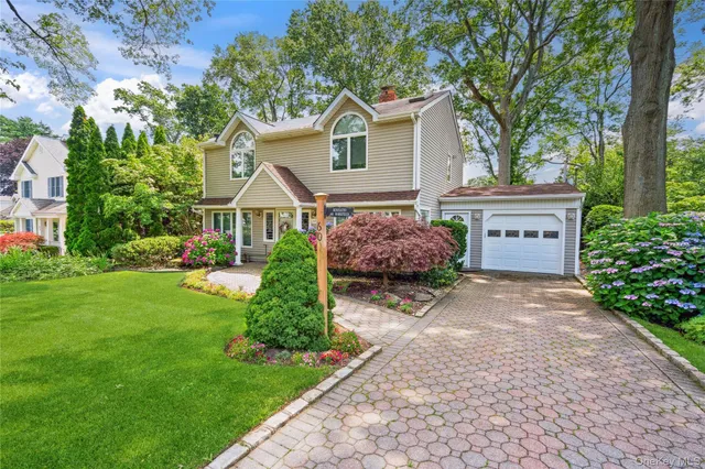 a front view of a house with a garden and trees