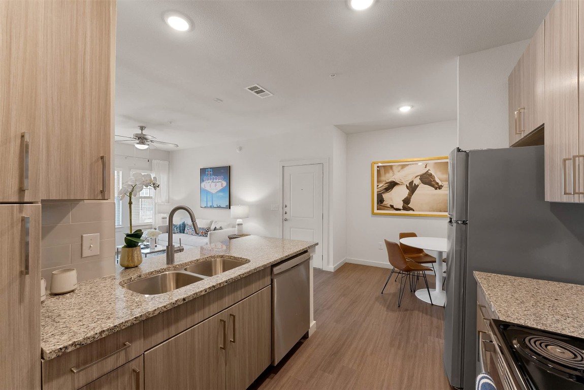 13301 Dessau Road, Unit 3206 Austin, TX 78754 - Photo 6 of 17 a kitchen with stainless steel appliances granite countertop a sink dishwasher a refrigerator and a stove with wooden floor
