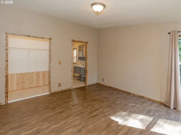 an empty room with wooden floor & closet and windows