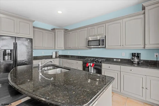 a kitchen with stainless steel appliances granite countertop a stove top oven a sink a dining table and chairs