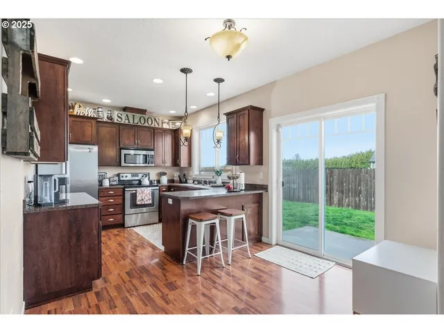 a open kitchen with stainless steel appliances granite countertop a stove refrigerator and a view of living room