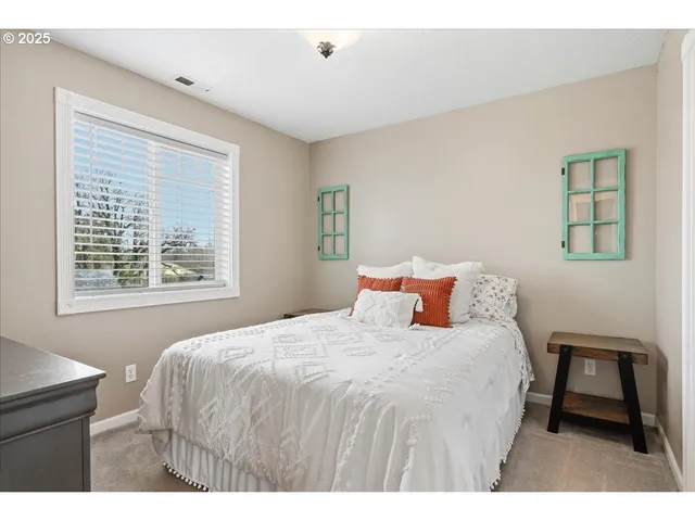 a bedroom with a bed a painting on the wall and a window
