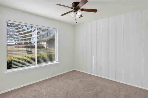 a view of an empty room with a window and a ceiling fan