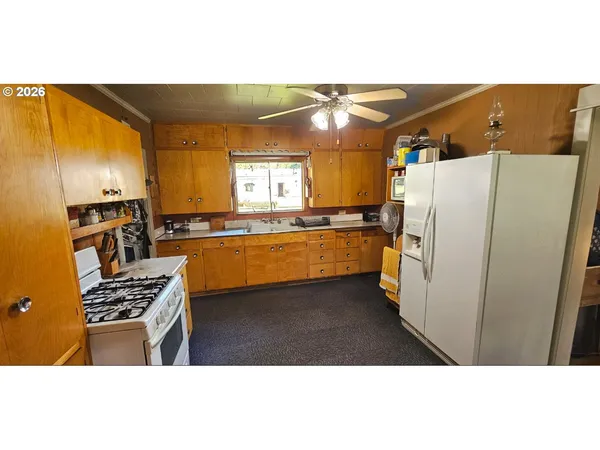 a kitchen with granite countertop a refrigerator a stove a sink and dishwasher