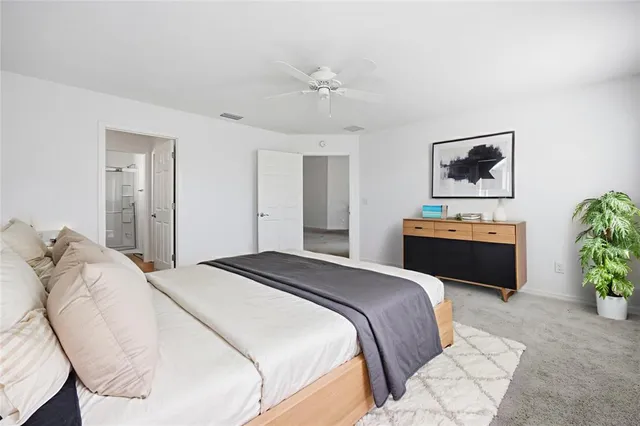 a bedroom with a bed large mirror and vanity