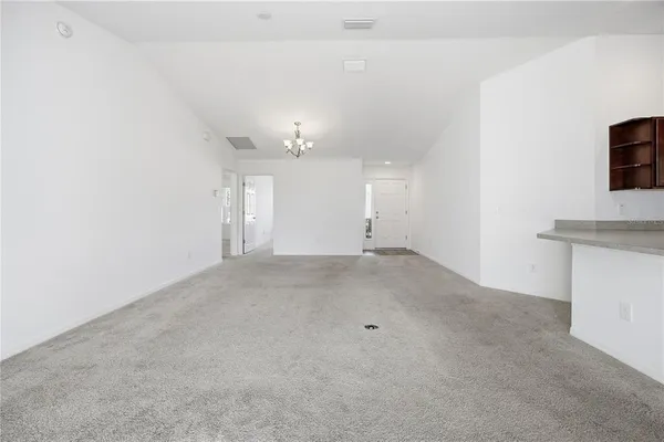 an empty room with a chandelier fan and windows